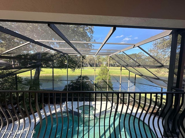 view of pool featuring glass enclosure, a water view, and an in ground hot tub