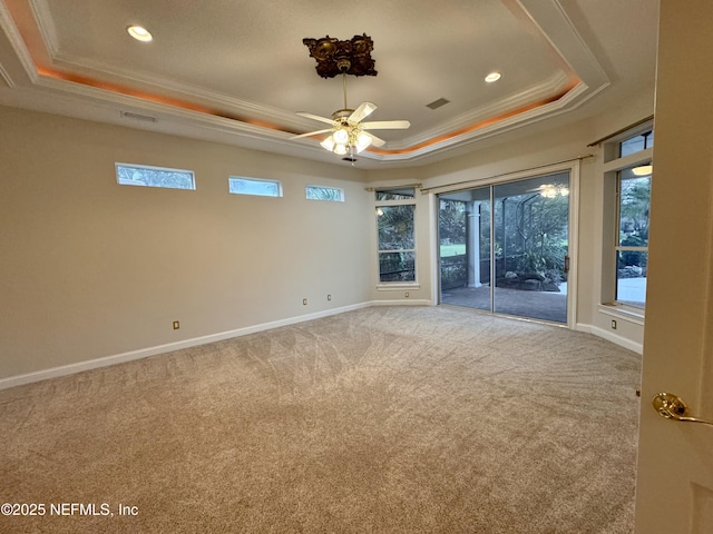 carpeted spare room with a raised ceiling, ornamental molding, and ceiling fan