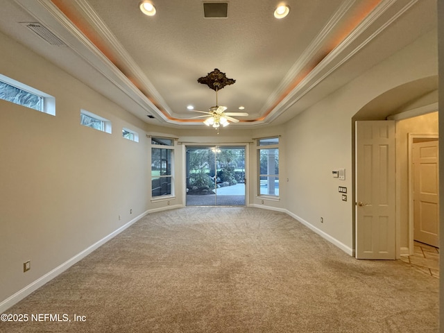 carpeted empty room with ceiling fan, ornamental molding, and a raised ceiling