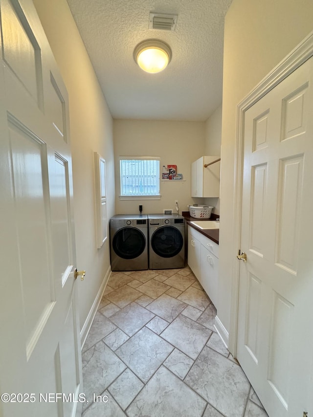 laundry room featuring washer and clothes dryer, cabinets, and a textured ceiling