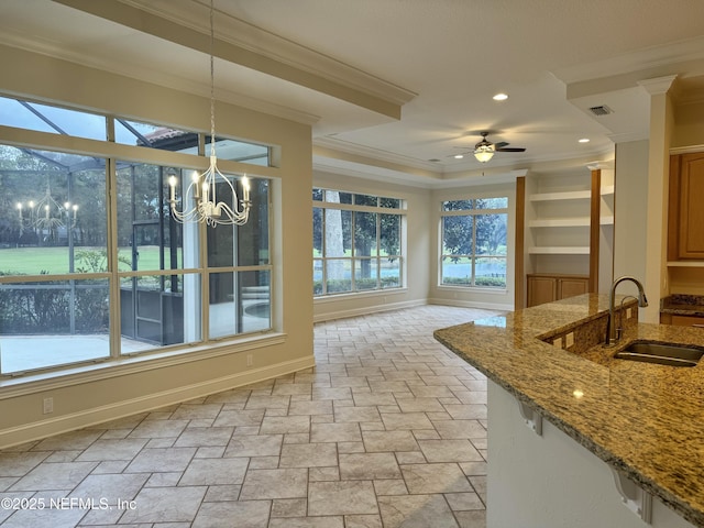 unfurnished sunroom with ceiling fan with notable chandelier and sink