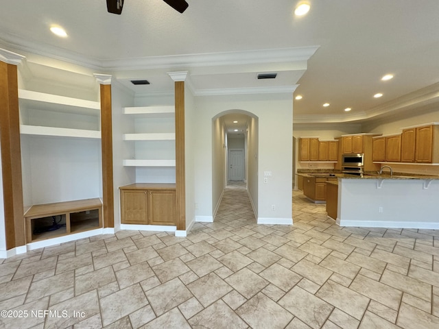 unfurnished living room with ceiling fan, ornamental molding, sink, and built in features