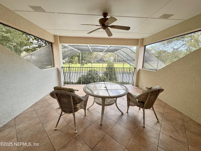 sunroom with a water view, ceiling fan, and a wealth of natural light