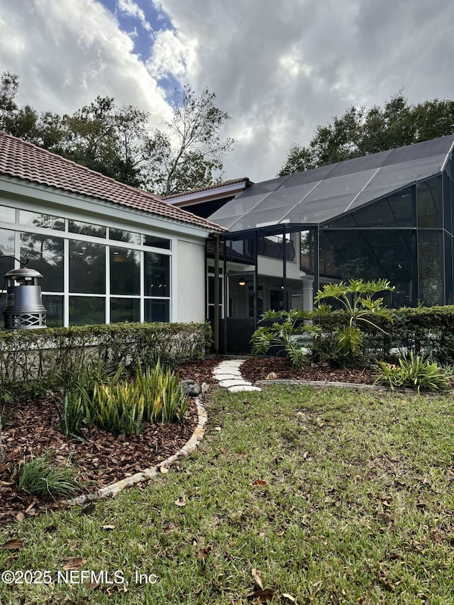 rear view of property with a lanai and a lawn