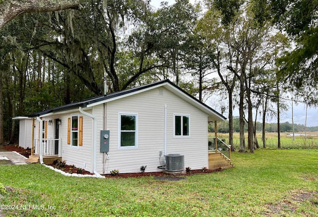 view of side of property featuring cooling unit and a yard