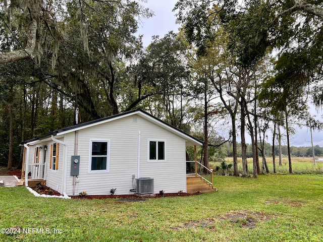 view of side of home featuring a lawn and cooling unit