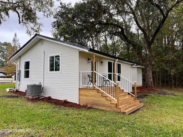 ranch-style home featuring cooling unit and a front yard