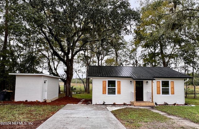 view of front of home with a front yard and a storage shed