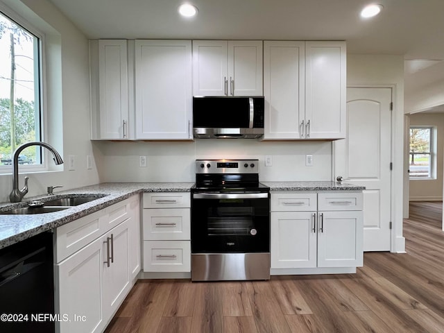 kitchen featuring stainless steel appliances, plenty of natural light, sink, white cabinetry, and light hardwood / wood-style flooring