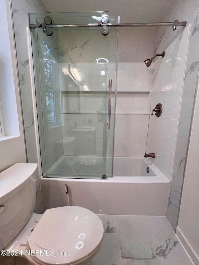 bathroom featuring combined bath / shower with glass door and toilet