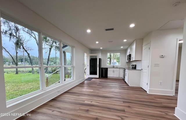 kitchen featuring stainless steel appliances, white cabinetry, light stone countertops, sink, and hardwood / wood-style floors