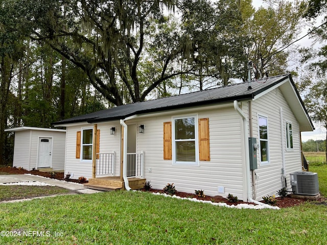 single story home featuring cooling unit, a front yard, and a storage unit