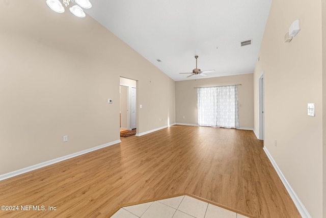 unfurnished living room featuring ceiling fan with notable chandelier, light hardwood / wood-style flooring, and high vaulted ceiling