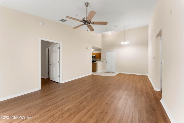 unfurnished living room with hardwood / wood-style flooring and ceiling fan with notable chandelier