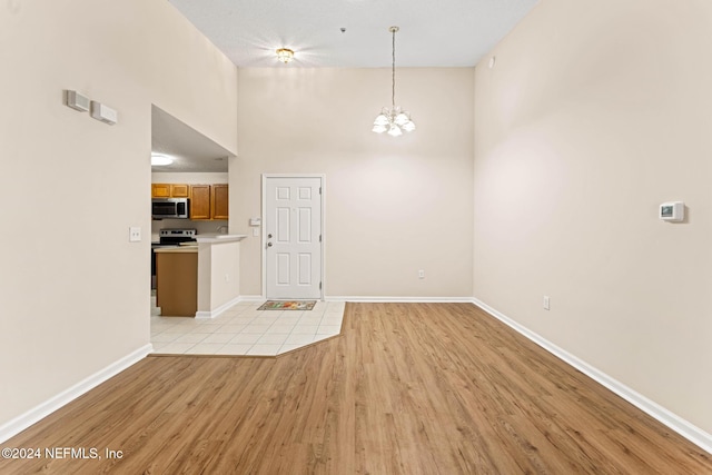 interior space featuring a high ceiling, an inviting chandelier, and light wood-type flooring