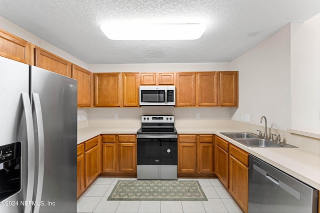 kitchen with light tile patterned floors, a textured ceiling, sink, and appliances with stainless steel finishes