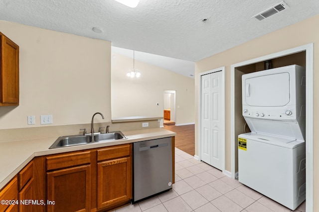 kitchen featuring stacked washer and clothes dryer, a textured ceiling, hanging light fixtures, sink, and stainless steel dishwasher