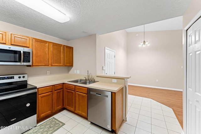 kitchen with stainless steel appliances, sink, kitchen peninsula, light hardwood / wood-style flooring, and a notable chandelier