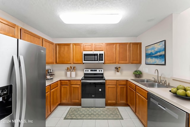 kitchen featuring a textured ceiling, stainless steel appliances, sink, and light tile patterned floors