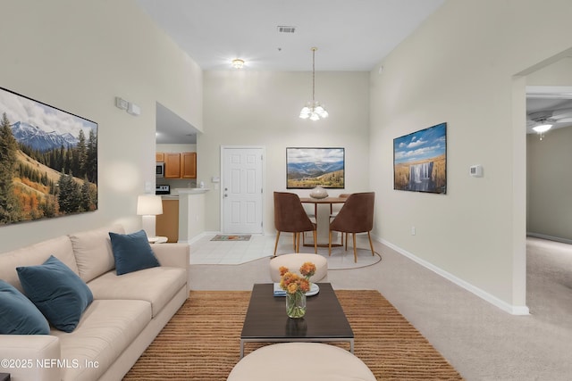 living area with light colored carpet, a high ceiling, baseboards, and a chandelier