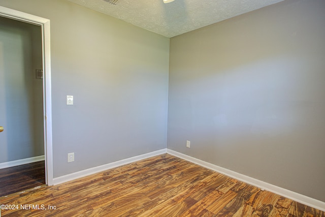 spare room featuring dark hardwood / wood-style floors and a textured ceiling