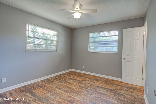 spare room with a textured ceiling, dark hardwood / wood-style flooring, and plenty of natural light