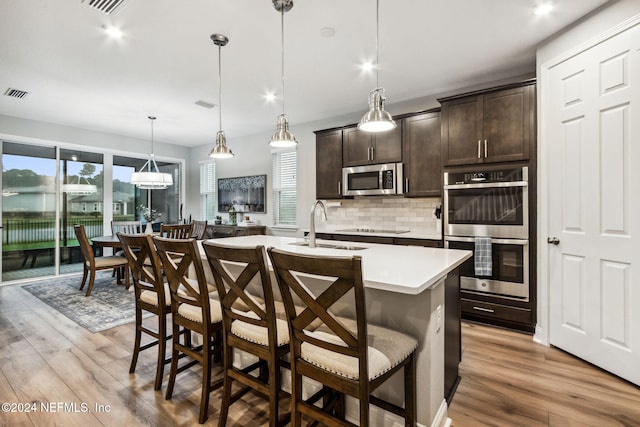 kitchen featuring a kitchen breakfast bar, dark brown cabinetry, light hardwood / wood-style floors, and stainless steel appliances