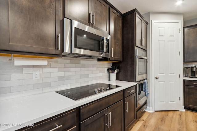 kitchen with dark brown cabinets, decorative backsplash, appliances with stainless steel finishes, and light hardwood / wood-style floors