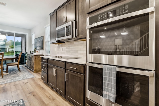 kitchen featuring light hardwood / wood-style floors, decorative backsplash, dark brown cabinetry, appliances with stainless steel finishes, and decorative light fixtures