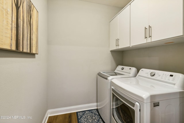 laundry room with dark wood-type flooring, cabinets, and washing machine and clothes dryer