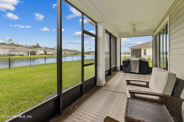 sunroom / solarium with a water view and ceiling fan