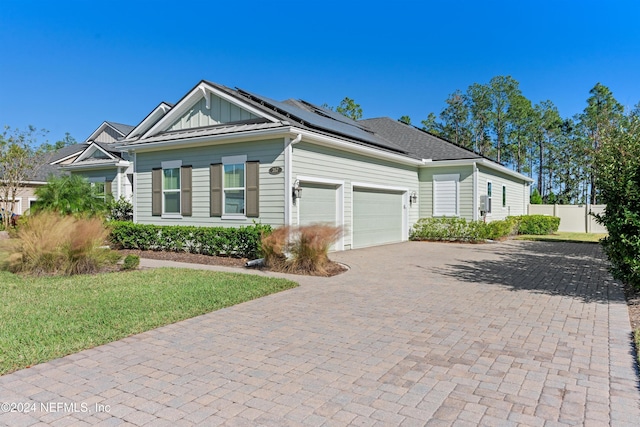 view of front of house with a front yard, solar panels, and a garage