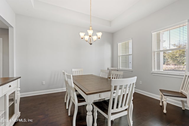 dining area with a raised ceiling, a notable chandelier, and dark hardwood / wood-style flooring