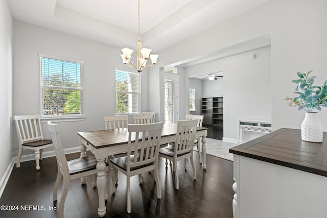 dining area featuring a tray ceiling, ceiling fan with notable chandelier, and dark hardwood / wood-style floors