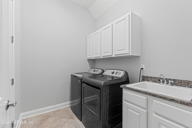 laundry area with light tile patterned flooring, cabinets, sink, and washing machine and clothes dryer