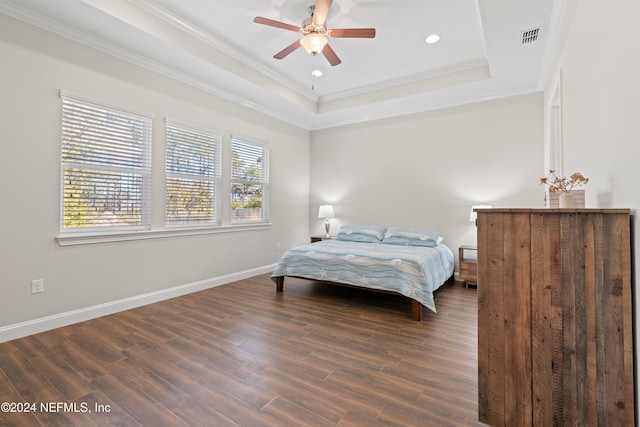 bedroom with a tray ceiling, ceiling fan, dark hardwood / wood-style flooring, and ornamental molding