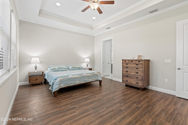 bedroom with ceiling fan, dark hardwood / wood-style flooring, crown molding, and a tray ceiling