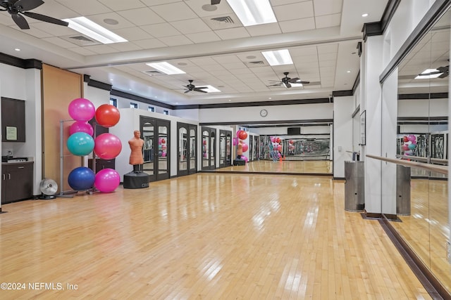 workout area with light wood-type flooring, a paneled ceiling, and basketball hoop