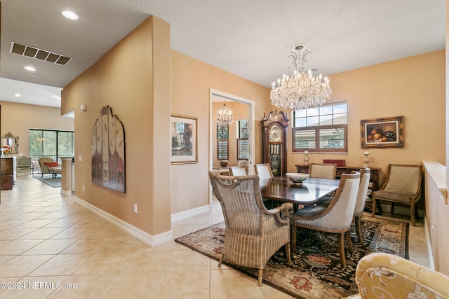 tiled dining space featuring a healthy amount of sunlight and an inviting chandelier