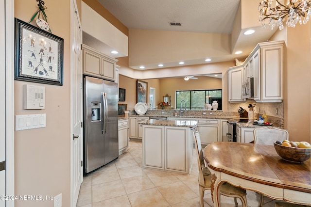 kitchen with kitchen peninsula, appliances with stainless steel finishes, light stone countertops, a center island, and vaulted ceiling