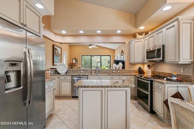 kitchen with stainless steel appliances, light tile patterned flooring, kitchen peninsula, a center island, and vaulted ceiling