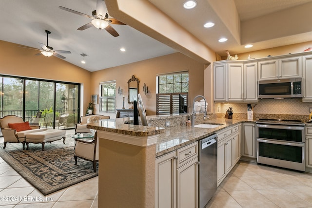 kitchen with stainless steel appliances, light stone counters, vaulted ceiling, kitchen peninsula, and sink