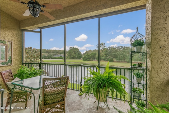 sunroom / solarium with ceiling fan and a water view