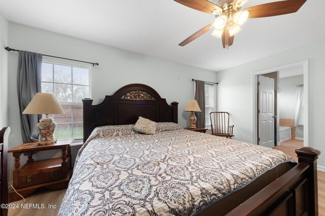 bedroom with multiple windows, wood-type flooring, connected bathroom, and ceiling fan