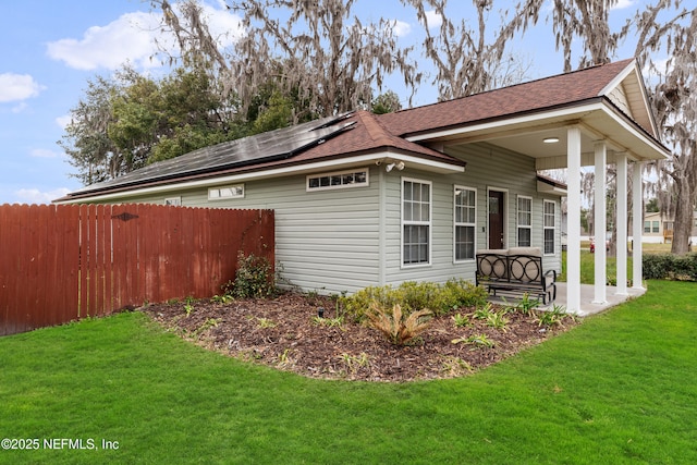 view of side of property with a lawn, a patio, and solar panels