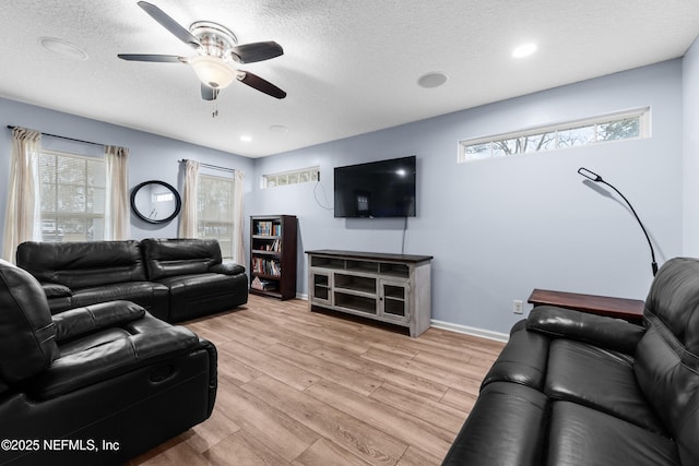 living room featuring ceiling fan, plenty of natural light, a textured ceiling, and light wood-type flooring