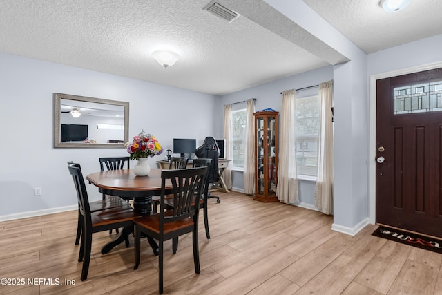 dining space with light hardwood / wood-style floors and a textured ceiling