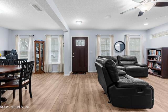 living room featuring ceiling fan, a textured ceiling, and light wood-type flooring