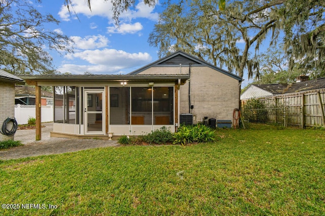 back of property with a yard, fence, a sunroom, and brick siding