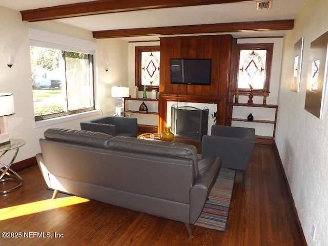 living room featuring plenty of natural light, beamed ceiling, and wood finished floors